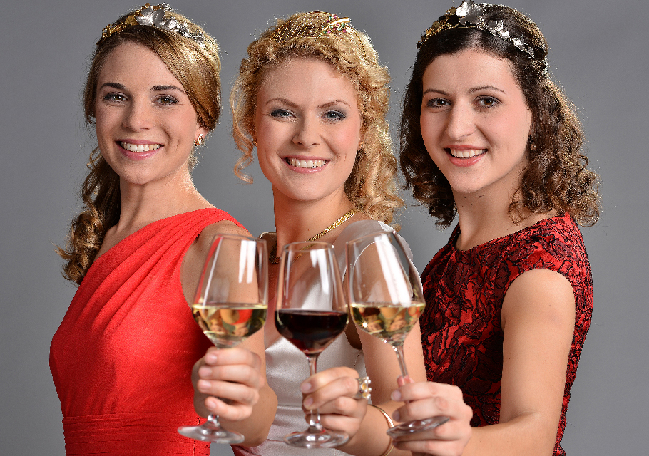 Crowned wine queens holding up three glasses of wine